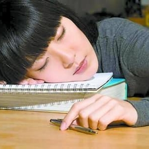 学生趴在课桌上午睡害处多